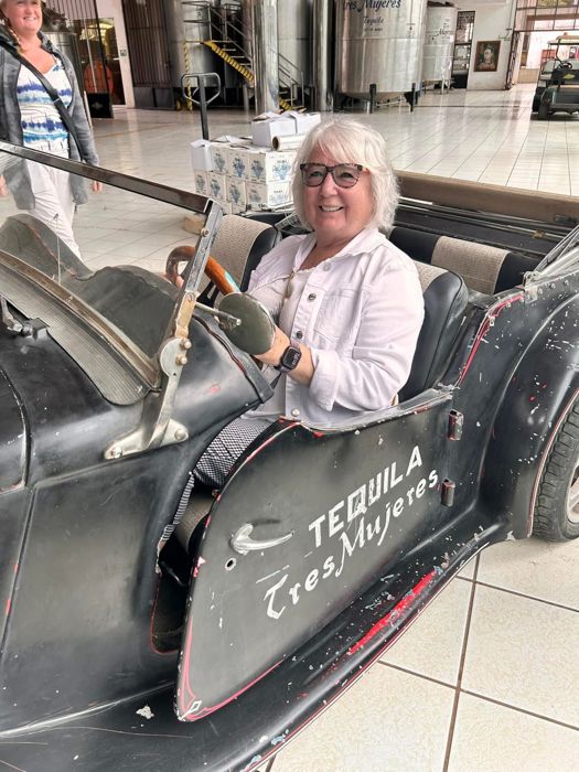 Guest posing in a vintage car at a distillery