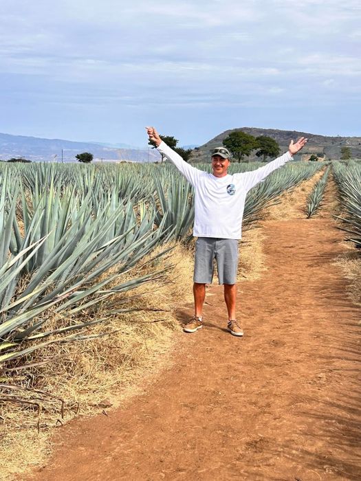 Guest with arms raised in a blue agave field