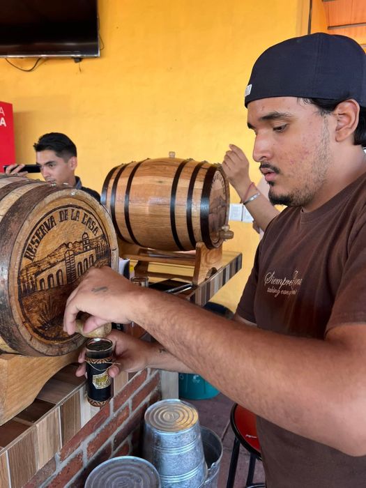 Bartender filling a drink from a small oak barrel