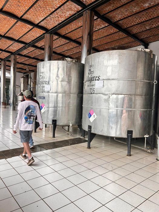 Visitor walking past stainless steel tequila tanks