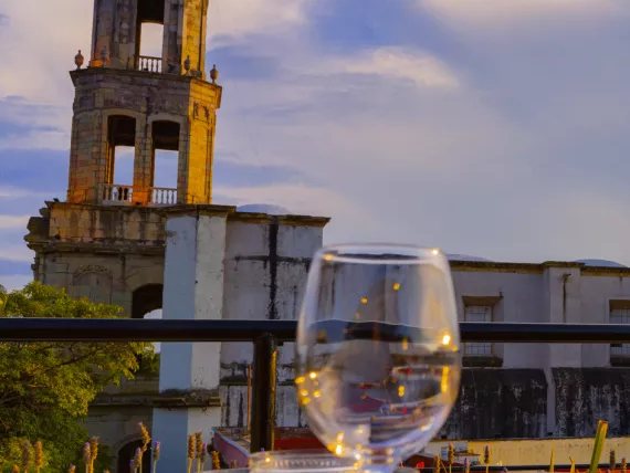 Stone bell tower and a wine glass on a terrace table at sunset